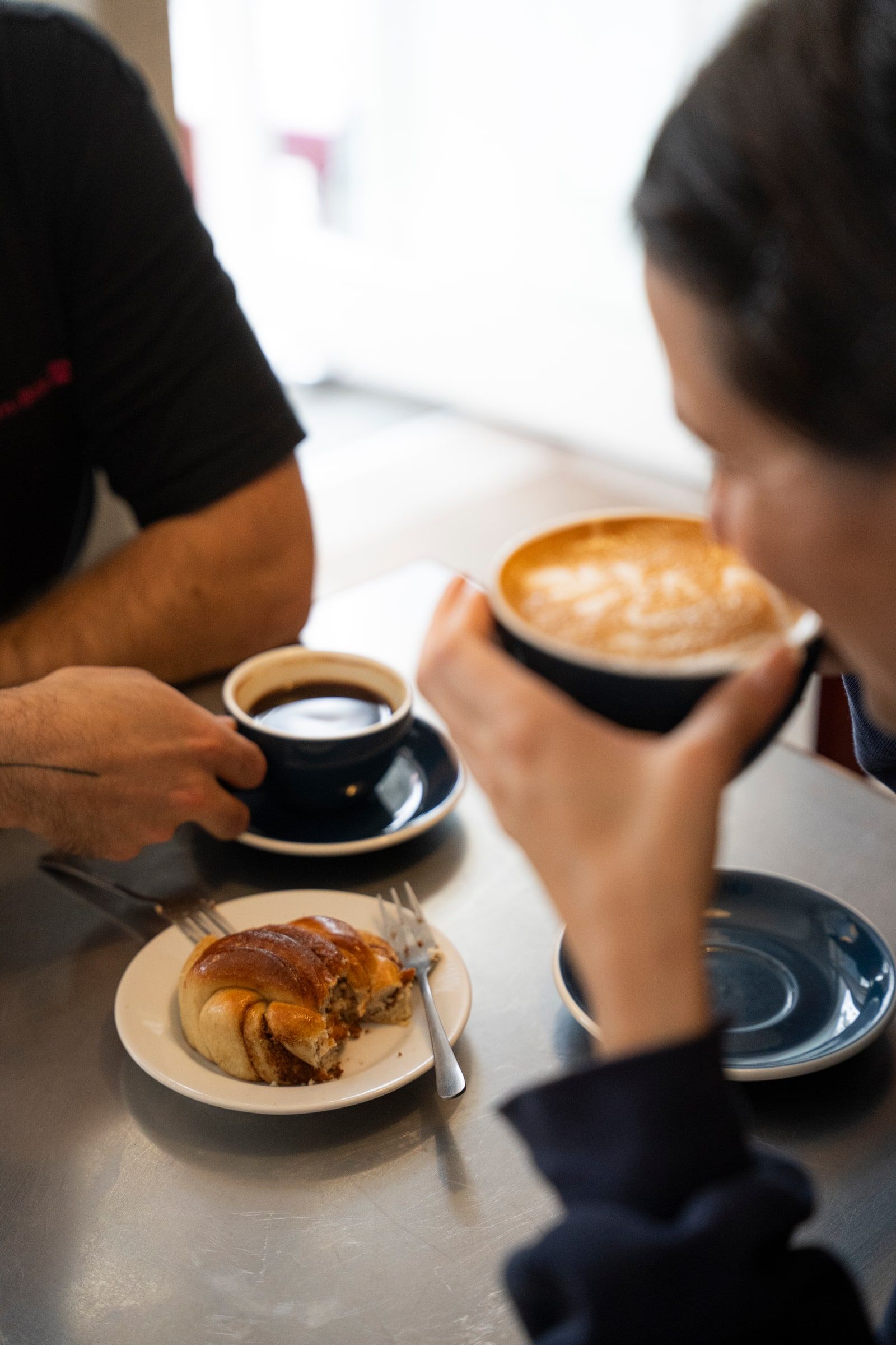 Zwei Menschen an einem Tisch mit Kaffee und einem Gebäckstück